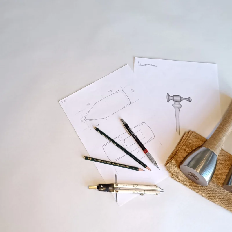 Études dessinées au compas et au crayon à côté d'un maillet terminé