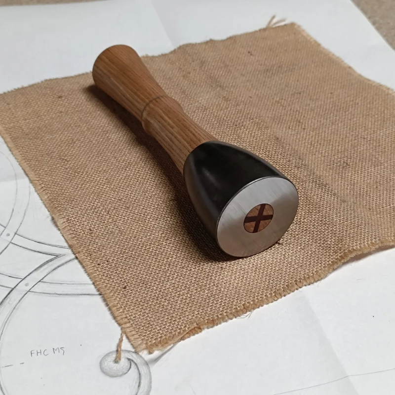 Maillet de sculpteur posé sur une toile de jute et un dessin d'atelier